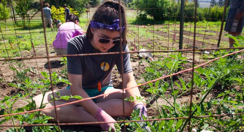 a teen works in a garden during a service project with outward bound